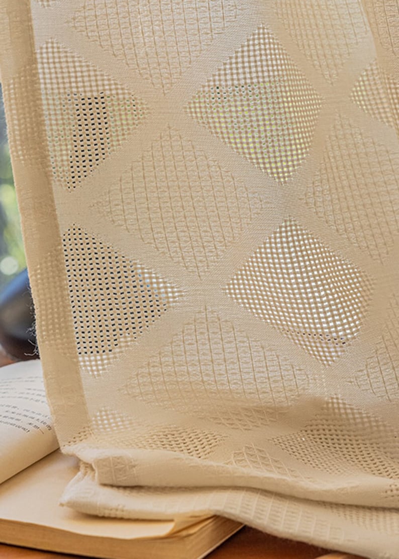 Puede incluir: Primer plano de una cortina transparente de color crema con un patr&oacute;n geom&eacute;trico de c&iacute;rculos y cuadrados superpuestos. La cortina est&aacute; hecha de una tela ligera y transpirable.