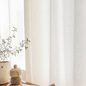 May include: White sheer curtains with a subtle herringbone pattern hang in a window. A small potted plant and a wooden spool of twine are on a table in front of the curtains.