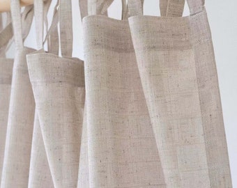 May include: Set of three beige linen curtains with a woven texture, hanging from a wooden rod. The curtains have loops at the top for hanging.