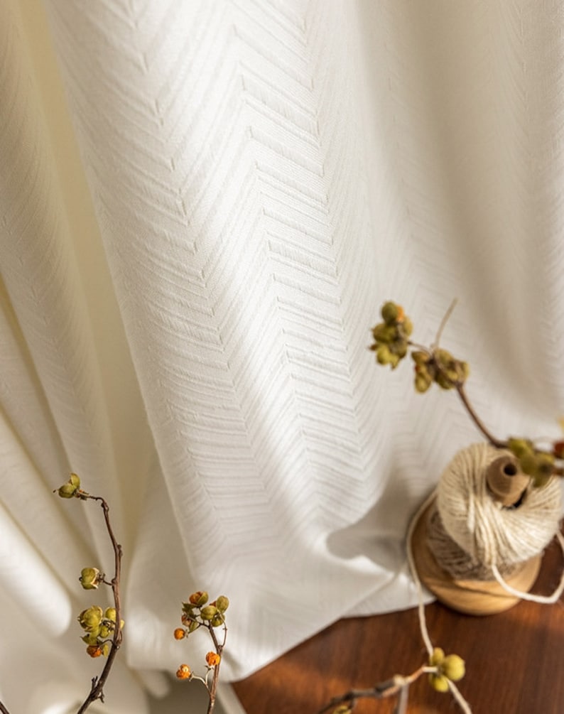 May include: White sheer curtains with a subtle herringbone pattern. The curtains are hanging in a window and are illuminated by natural light.