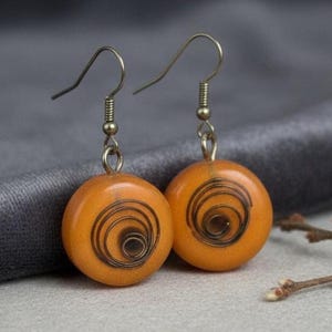 Handmade epoxy resin earrings with a spiral copper wire element.