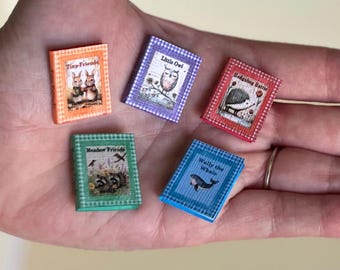 May include: Five miniature books with colorful gingham covers. The orange book is titled Tiny Friends, the purple book is Little Owl, the red book is Hedgehog Hattie, the green book is Meadow Friends, and the blue book is titled Wally the Whale.