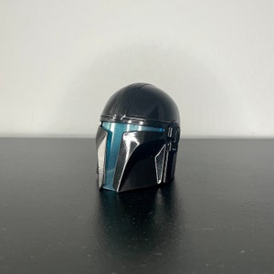 Puede incluir: Un casco negro con una visera azul. El casco tiene una superficie texturizada y un diseño elegante.