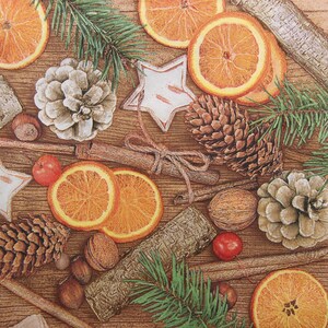 2 oder 4 Stück Papierservietten für das Handwerk, Lebkuchen, getrocknete Orangenscheiben, Walnüsse, Haselnüsse Zimtstangen, Zapfen auf braunem Bretter Hintergrund