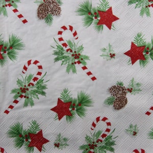 2 ou 4 serviettes en papier pour découpage, bâtonnets de bonbons de Noël, brindilles de baies de houx, pommes de pin et bouquets de décoration d'étoiles sur fond blanc