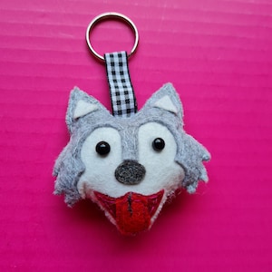 May include: A gray felt wolf head keychain with black and white checkered ribbon and a red felt tongue.