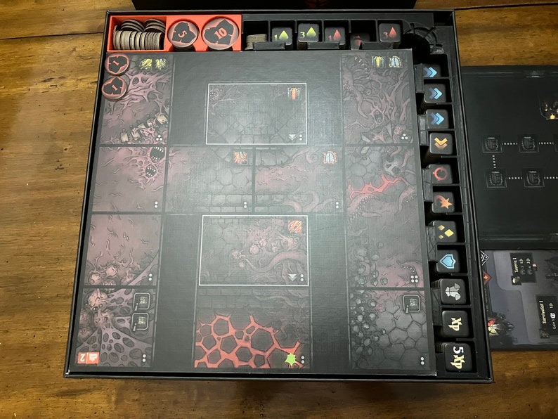 K&ouml;nnte beinhalten: Ein Brettspiel-Set mit einem dunklen, dungeonartigen Thema. Das Spielbrett ist in quadratische Kacheln mit detaillierten Illustrationen unterteilt. Enth&auml;lt verschiedene Spielsteine, W&uuml;rfel und Kartenhalter. Die Farbpalette ist haupts&auml;chlich dunkelgrau, schwarz und rot.