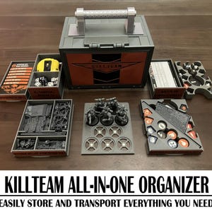 Könnte beinhalten: Eine graue Plastik-Aufbewahrungsbox mit einem Griff, auf der vorne "KILLTEAM" steht. Die Box ist geöffnet und enthält verschiedene Spielteile, darunter Miniaturen, Würfel und Karten. Die Box ist so konzipiert, dass sie alle Komponenten des Kill Team-Spiels aufbewahrt und transportiert.