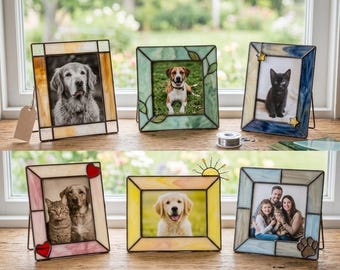 Könnte beinhalten: Eine Sammlung von Glasmalerei-Fotorahmen, die jeweils ein anderes Foto enthalten. Die Rahmen weisen verschiedene Farben und Designs auf, darunter Herzen, Sterne und Pfotenabdrücke. Die Fotos zeigen Haustiere und eine Familie.