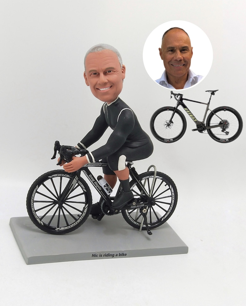 K&ouml;nnte beinhalten: Figur eines Radfahrers auf einem schwarz-wei&szlig;en Fahrrad. Der Radfahrer tr&auml;gt einen schwarz-wei&szlig;en Radanzug. Die Figur steht auf einem grauen Sockel mit dem Text "Nic is riding a bike". Im Hintergrund ein Bild eines Mannes und eines Fahrrads.