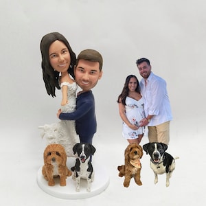 May include: A wedding cake topper featuring a bride and groom in a playful pose, with the bride being lifted by the groom. The couple is surrounded by four dogs, two brown and two black and white.