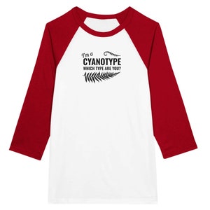 May include: White and red baseball tee shirt with the text "I'm a cyanotype which type are you?" in black lettering with a fern graphic.