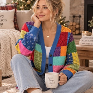 May include: A long-sleeve button-down cardigan featuring a vibrant patchwork design with various floral patterns in shades of red, blue, yellow, green, and purple. The garment has a solid blue trim along the neckline and front opening.