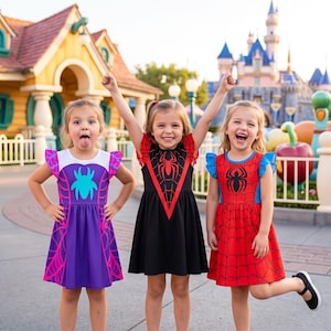 May include: Three short-sleeved dresses featuring spider-themed designs. One dress is purple with a white bodice and teal spider, one is black with a red spider emblem, and one is red with a black spider emblem and blue ruffled sleeves.