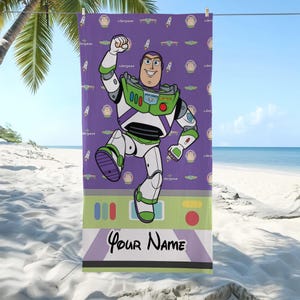 Puede incluir: Una toalla de playa morada con Buzz Lightyear de Toy Story. La toalla tiene un patr&oacute;n repetido de la cara de Buzz Lightyear, cohetes y la palabra "Lightyear". La parte inferior de la toalla tiene el texto "Your Name".