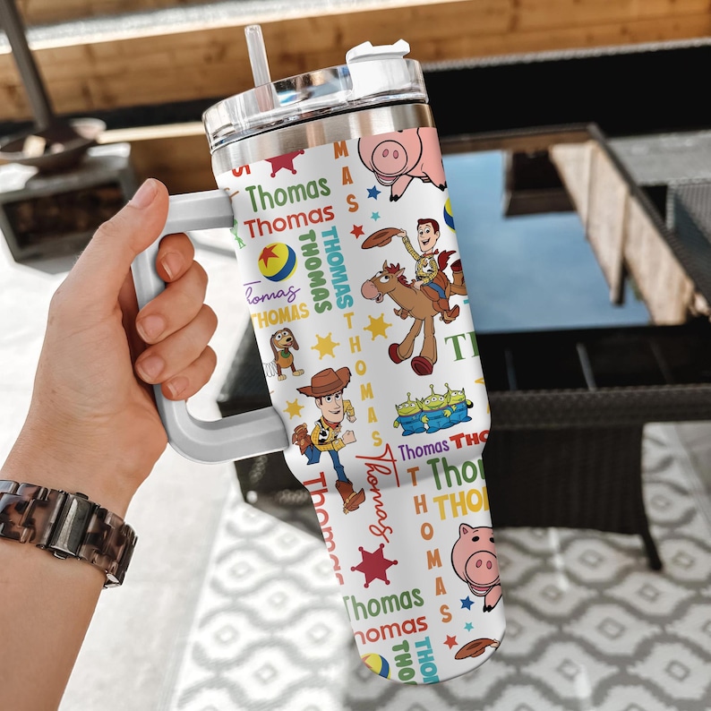 Pu&ograve; includere: Un bicchiere bianco in acciaio inossidabile con manico e coperchio trasparente dotato di cannuccia. L'esterno &egrave; decorato con un motivo ripetuto di personaggi di Toy Story, tra cui Woody, Bullseye, Hamm e gli alieni, insieme al nome Thomas.