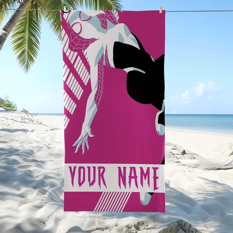 May include: A pink beach towel featuring a stylized illustration of a superhero in a dynamic pose. The character is depicted in white and black, with a web-like design. The towel includes the text "YOUR NAME" in a bold, stylized font.