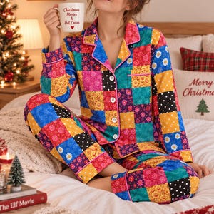 May include: A long-sleeved button-down pajama set featuring a vibrant patchwork pattern of floral prints in blue, yellow, pink, and black with white polka dots. The set includes a collared shirt with pink piping and matching pants.
