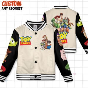 Może przedstawiać: Kremowa kurtka typu varsity z postaciami z Toy Story. Kurtka ma czarne rękawy z grafiką postaci, biało-czarny kołnierz i mankiety w paski oraz napis "TOY STORY" z przodu.