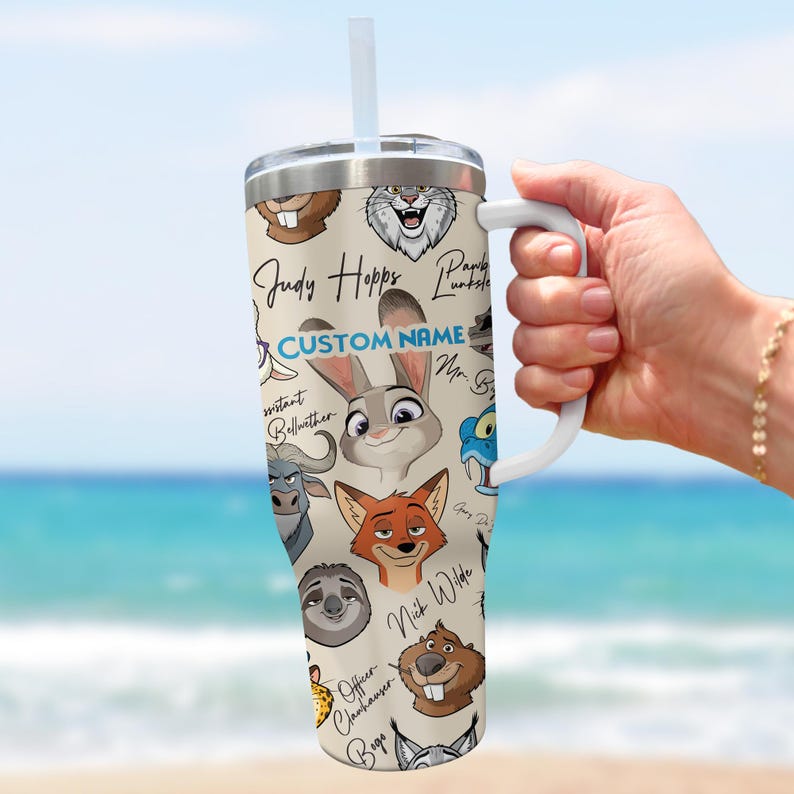 Puede incluir: Un vaso de acero inoxidable con ilustraciones de personajes de dibujos animados y el texto "Judy Hopps" y "Custom Name". El vaso tiene un asa blanca y una pajita, perfecto para bebidas fr&iacute;as.