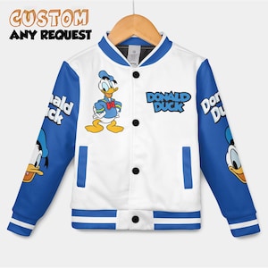 Op de afbeelding: Witte en blauwe varsity jas met Donald Duck. De jas heeft blauwe mouwen met Donald Duck graphics en de woorden "Donald Duck" op de voorkant. De tekst "CUSTOM ANY REQUEST" is ook aanwezig.