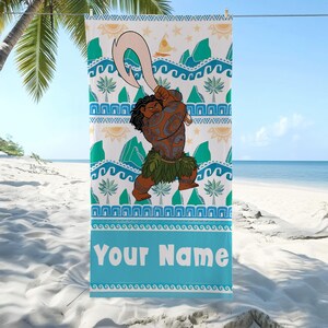 May include: A beach towel featuring a cartoon illustration of a Polynesian character holding a large hook. The towel has a white background with teal, green, and yellow patterns, including waves, mountains, and suns. The text "Your Name" is displayed in a blue banner.