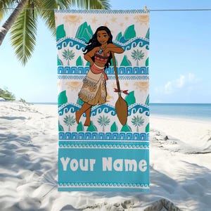 May include: A beach towel featuring a cartoon character with long black hair, wearing a patterned outfit, and holding a paddle. The towel has a blue border with the text "Your Name" and a tropical design with waves, palm trees, and mountains.