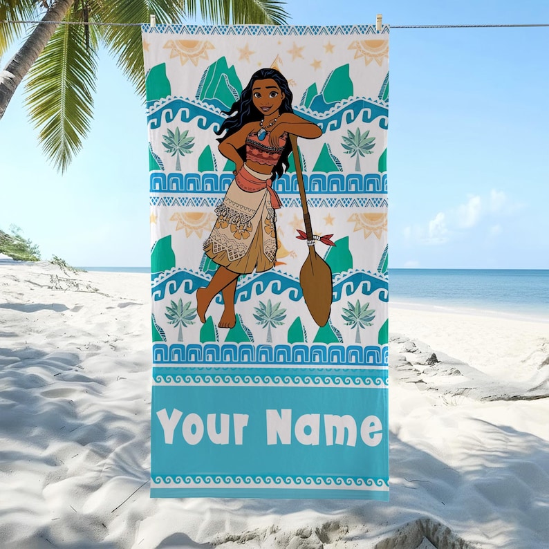 May include: A beach towel featuring a cartoon character with long black hair, wearing a patterned outfit, and holding a paddle. The towel has a blue border with the text "Your Name" and a tropical design with waves, palm trees, and mountains.