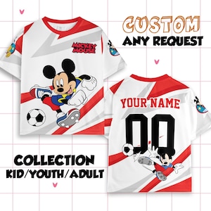 以下が含まれることがあります： 赤色のアクセントとミッキーマウスのグラフィックが施された白いTシャツ。1枚はサッカーをするミッキー、もう1枚は背中に名前と番号が入っています。「CUSTOM ANY REQUEST」と「COLLECTION KID/YOUTH/ADULT」の文字。