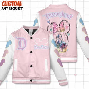 May include: Pink and white varsity jacket with a Disneyland theme. The front features a large "D" and a Mickey Mouse head with the text "Your Name". The back displays "Disneyland" and a Minnie Mouse bow with a castle illustration. The sleeves have cloud and Mickey Mouse head accents.