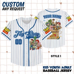May include: A white baseball jersey with blue pinstripes featuring Toy Story character graphics on the front and back. The front displays the Toy Story logo and the number 00. The back shows a box with characters and the text YOU'VE GOT A FRIEND IN ME.