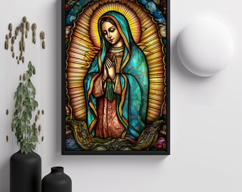 May include: A framed stained-glass style artwork depicting a religious figure with hands clasped in prayer. The figure is draped in a teal blue robe and veil, with a halo of golden light radiating behind. The artwork is set against a white wall.