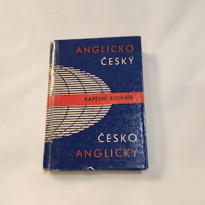 May include: A small, rectangular book with a dark blue cover. The cover features the words "ANGLICKO ČESKÝ" and "ČESKO ANGLICKY" in white, with a red stripe and a white globe design. The book is a pocket dictionary.