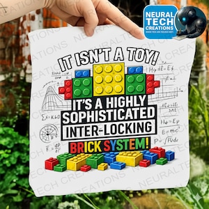 May include: A white print featuring colorful interlocking toy bricks with the text "IT ISN'T A TOY! IT'S A HIGHLY SOPHISTICATED INTER-LOCKING BRICK SYSTEM!" The print also includes mathematical equations and diagrams.