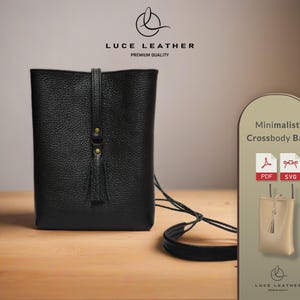 May include: Black leather crossbody bag with a tassel and adjustable strap. The bag has a rectangular shape and a minimalist design. The image includes the text "LUCE LEATHER" and "Minimalist Crossbody Bag".