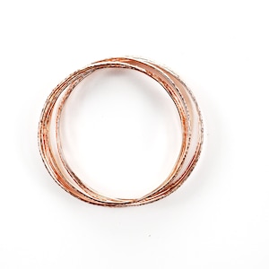 May include: A set of five gold-toned bangles with a textured finish. The bangles are stacked on top of each other.