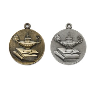 May include: Two round metal medallions with a gold and silver finish. Each medallion features a raised image of an oil lamp with a flame and a stack of books. The medallions are perfect for awards or recognition.