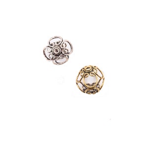 May include: Two metal bead caps, one silver and one gold, with intricate floral designs. The caps are designed to be used as end caps for jewelry making.