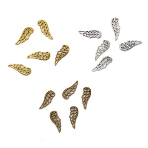 May include: A collection of silver and gold angel wing charms. The charms are delicate and intricate, with a detailed design. They are perfect for adding a touch of whimsy to jewelry or crafts.
