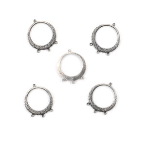 May include: Five silver-toned metal rings with ornate designs and three loops on each ring. The rings are for jewelry making.