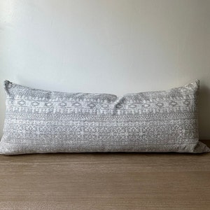 May include: A long, rectangular throw pillow with a white background and a gray geometric pattern.