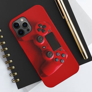 May include: A red phone case with a black PlayStation controller design. The case has a camera cutout and a red background.