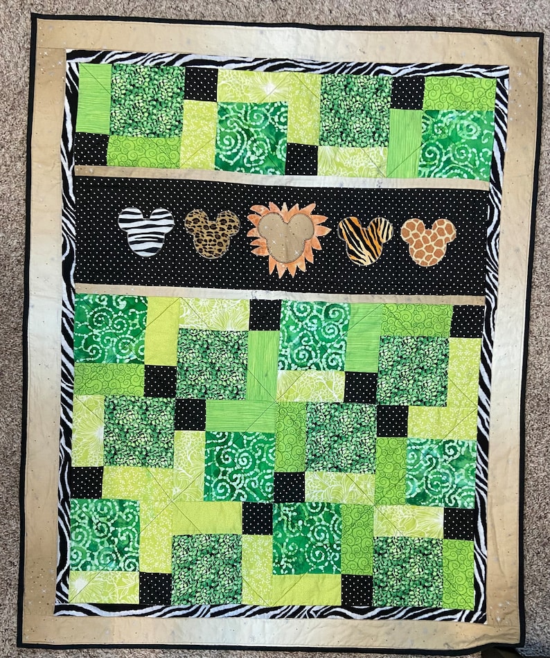 Puede incluir: Un edred&oacute;n hecho a mano con un tema de la jungla. El edred&oacute;n presenta un dise&ntilde;o de patchwork en tonos de verde, negro y blanco. El centro tiene dise&ntilde;os en forma de Mickey Mouse con estampados de animales. El borde es estampado de cebra.