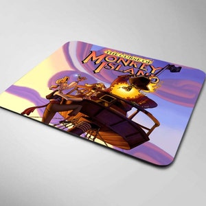 Puede incluir: Una alfombrilla de ratón morada y amarilla con una imagen de dibujos animados de un personaje pirata del videojuego "The Curse of Monkey Island". El texto "The Curse of Monkey Island" está impreso en blanco en la alfombrilla de ratón.