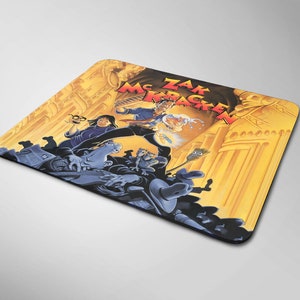 May include: A yellow and brown mousepad with a cartoon image of a group of people, including a man with a red shirt and the text "Zak McKracken" on it.