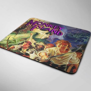 Puede incluir: Un ratón de ordenador colorido con la portada del clásico videojuego "The Secret of Monkey Island". La imagen muestra a un pirata sosteniendo una espada, con una calavera y huesos cruzados en el fondo.