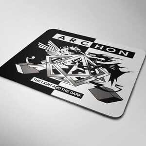 May include: A rectangular mouse pad featuring a black and white split design. The text ARCHON appears at the top, and THE LIGHT AND THE DARK is at the bottom. A central geometric shape is flanked by a white bird-like figure and a black dragon-like figure.