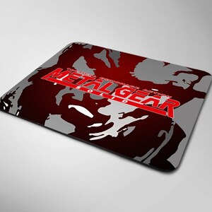 May include: A red and gray mousepad with the words "Tactical Espionage Action Metal Gear Solid" in white text.