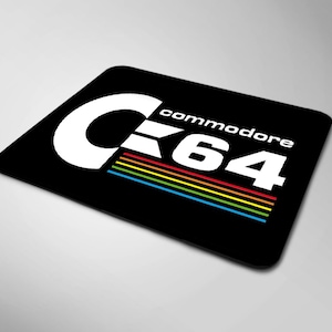 Op de afbeelding: Zwarte muismat met een wit Commodore 64 logo en regenboogstrepen.