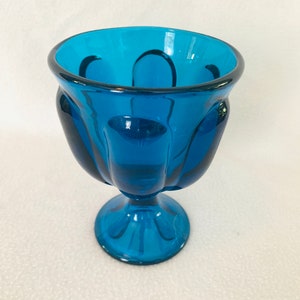 May include: A teal blue glass bowl with a fluted design and a pedestal base.